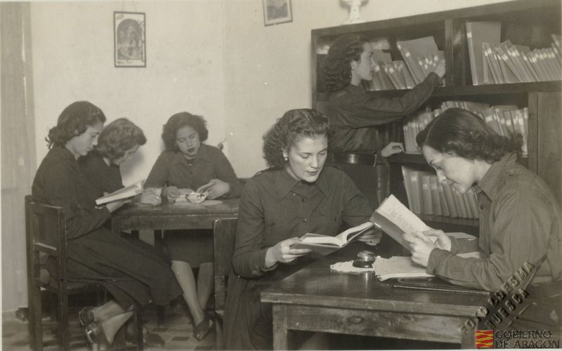 Chicas con el uniforme de la Sección Femenina leyendo en la biblioteca. Foto Luesma